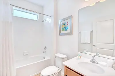 a white bathroom with a sink and a toilet at Family Resort - 6BR Mansion - Private Pool, Home Theater, BBQ and More in Kissimmee