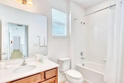 a white bathroom with a sink and a toilet and a tub at Family Resort - 6BR Mansion - Private Pool, Home Theater, BBQ and More in Kissimmee