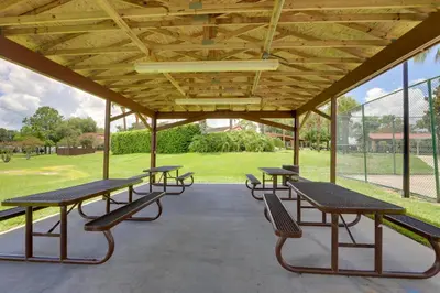 a group of picnic tables and benches under a pavilion at Steps to Pool Winter Garden House with Lanai! in Orlando