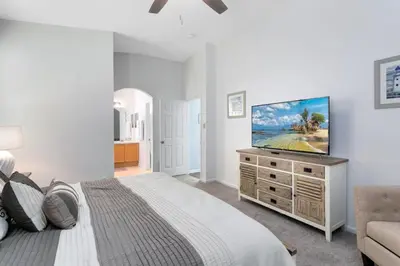a bedroom with a bed and a flat screen tv at Immaculate 4 bedrooms 3 bathroom in Windsor Palms villa in Kissimmee