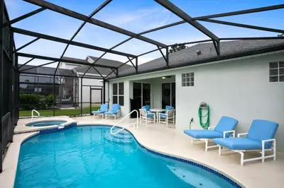 a swimming pool with blue chairs and a patio at Immaculate 4 bedrooms 3 bathroom in Windsor Palms villa in Kissimmee