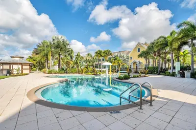 a swimming pool with palm trees and a house at 2 Bedroom Vacation Condo 2016 in Kissimmee