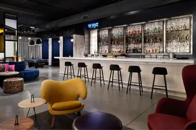 a bar with a yellow chair and tables and chairs at Aloft Orlando International Drive by Marriott in Orlando