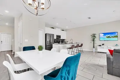 a dining room and living room with a white table and chairs at Family Resort - 4BR Home Near Disney - Private Pool, BBQ! in Kissimmee