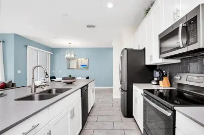 a kitchen with white cabinets and a black refrigerator at Family Resort - 4BR Home Near Disney - Private Pool, BBQ! in Kissimmee