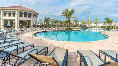 a swimming pool with chairs and a building at Family Resort - 4BR Home Near Disney - Private Pool, BBQ! in Kissimmee