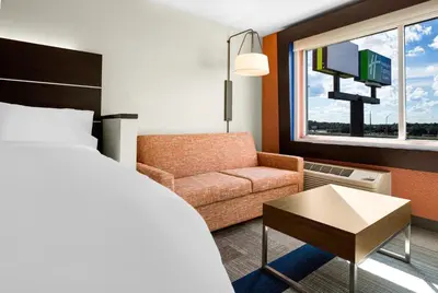 a bedroom with a bed and a couch and a tv at Holiday Inn Express & Suites Sanford - Lake Mary by IHG in Sanford
