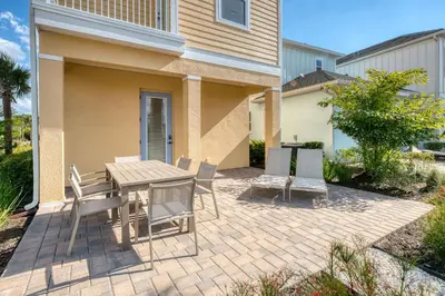 a patio with a table and chairs in front of a house at Lively Cottage Near Disney With Margaritaville Resort & Island H20 Waterpark Access - 2998Sr in Orlando