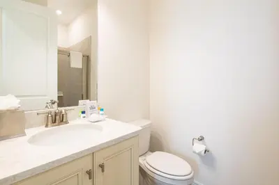 a white bathroom with a toilet and a sink at Lovely Green Cottage Near Disney With Margaritaville Resort & Island H20 Waterpark Access - 2982Sr in Orlando