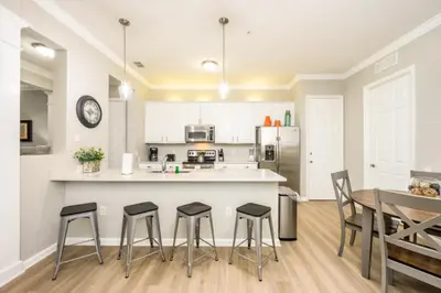 a kitchen with a table and some stools in it at Epic Universe Beautiful Modern Condo - Vista Cay Resort - 2007 in Orlando
