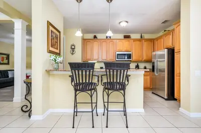 a kitchen with wooden cabinets and a island with bar stools at Premium Lake View Condo, Vista Cay - 1005 in Orlando