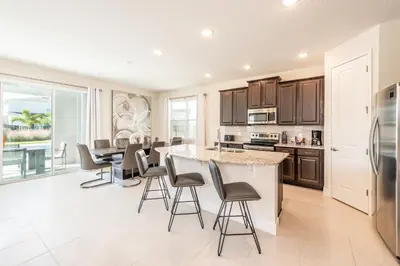 a kitchen with a large island with bar stools at Elegant Home Near Disney With Private Pool, Foosball Table, Themed Rooms And Waterpark & Resort Access At Encore Resorts Reunion - 365Sf in Kissimmee