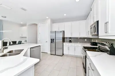 a kitchen with white cabinets and a stainless steel refrigerator at Modern Home Near Disney With Private Pool, Media, Game & Themed Rooms With Waterpark & Resort Access At Encore Resorts Reunion - 384Sf in Kissimmee