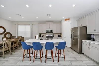 a kitchen with a table and blue chairs at Grand Home Near Disney With Private Pool, Air Hockey Table And Waterpark & Resort Access At Encore Resorts Reunion - 401Sf in Kissimmee