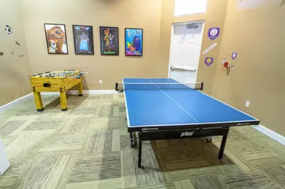 a blue ping pong table in a room with a table at Lakeview 6-Bedroom Retreat with Game Room, Private Pool, Spa & Resort Amenities - Ideal for Families & Groups in Kissimmee