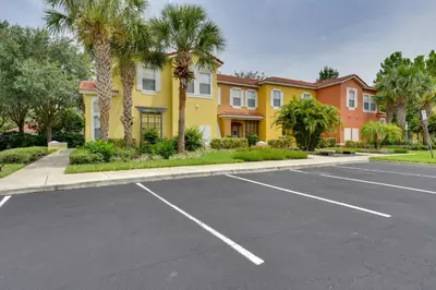 a parking lot in front of a building with palm trees at Near Disney and Epic Universe Home with Resort Perks in Kissimmee