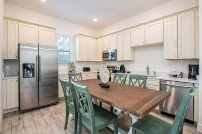 a kitchen with a wooden table and chairs and a refrigerator at Brilliant Cottage Near Disney With Margaritaville Resort & Island H2O Access - 8090Kd in Orlando