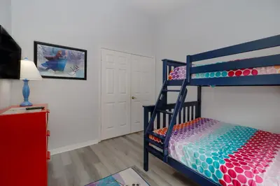 a bedroom with a bunk bed with a colorful bedspread at Making Dreams 4BR Family Villa with Pool and Game Room Near Disney Parks in Kissimmee
