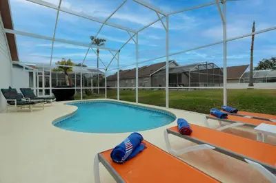 a swimming pool with orange benches around it at Making Dreams 4BR Family Villa with Pool and Game Room Near Disney Parks in Kissimmee