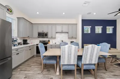 a kitchen with a wooden table and blue chairs at Pineapple Dream Cottage With Private Hot Tub Near Disney With Margaritaville Resort & Island H2O Access - 8000Sb in Orlando