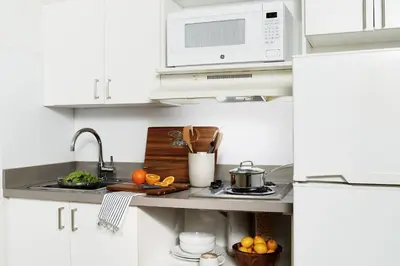 a white kitchen with a sink and a microwave at InTown Suites Extended Stay Orlando FL – Presidents Dr in Orlando
