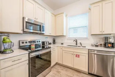 a kitchen with white cabinets and stainless steel appliances at Inviting Cottage Near Disney With Margaritaville Resort & Island H2O Access - 8009St in Orlando