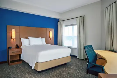a hotel room with a large bed and a chair at Residence Inn by Marriott Orlando at FLAMINGO CROSSINGS Town Center in Orlando