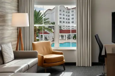 a living room with a couch and a chair and a window at Residence Inn by Marriott Orlando at FLAMINGO CROSSINGS Town Center in Orlando