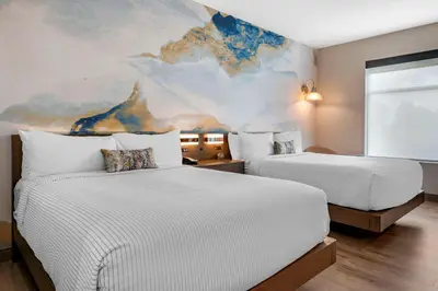 two beds in a room with a painting on the wall at Cambria Hotel Orlando Airport in Orlando