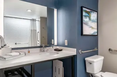 a bathroom with a sink and a toilet and a mirror at Cambria Hotel Orlando Airport in Orlando