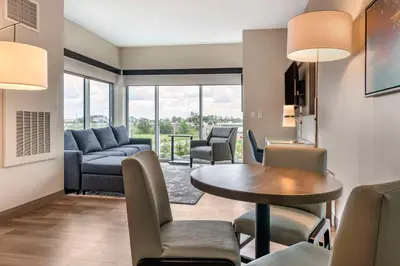 a living room with a couch and a table and chairs at Cambria Hotel Orlando Airport in Orlando