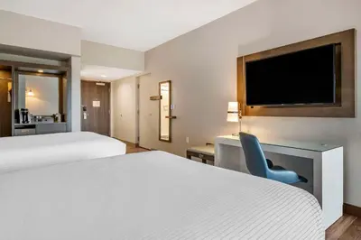 a hotel room with two beds and a blue chair at Cambria Hotel Orlando Airport in Orlando
