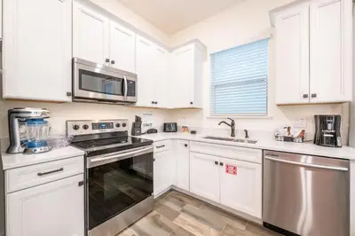 a kitchen with white cabinets and stainless steel appliances at Brilliant Cottage With Private Pool Near Disney With Margaritaville Island H2O Access - 8033St in Orlando