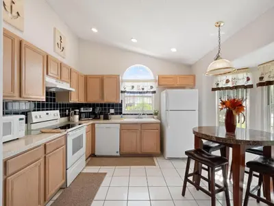 a kitchen with white appliances and a table with chairs at bsv_villa1607 in Orlando