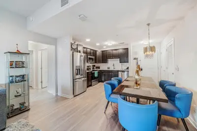 a kitchen and dining room with a table and blue chairs at Luxury 3BR resort Condo walking distance to Epic Universe, Convention center and Icon Park in Orlando