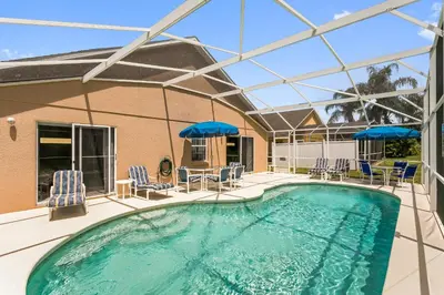 a swimming pool with chairs and umbrellas at South Facing Pool Deck - Private Outlook - Game Room - Family Friendly - Nr Disney in Orlando