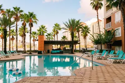 a swimming pool with chairs and palm trees at The Point by Edge in Orlando