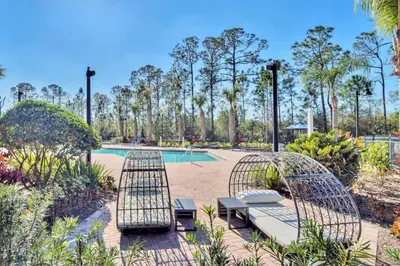 a patio with two chairs and a pool at Refreshing 3BR Apartment Near Disney - Pool and Hot Tub! in Orlando