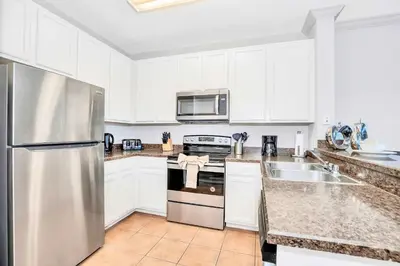 a kitchen with white cabinets and a stainless steel refrigerator at Luxury 3BR Near Disney - Pool in Orlando