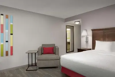 a bedroom with a bed and a chair with a red pillow at Hampton Inn & Suites Orlando North Altamonte Springs in Orlando