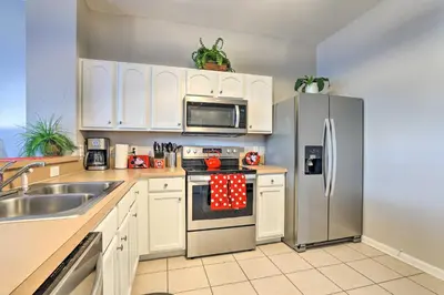 a kitchen with white cabinets and a stainless steel refrigerator at Private Cocktail Pool Kissimmee Resort Retreat! in Orlando