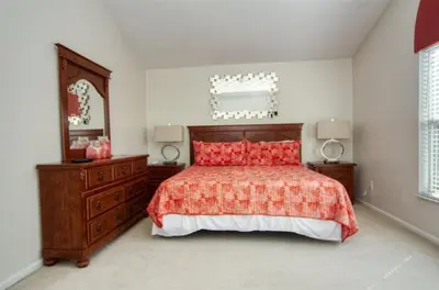 a bedroom with a bed and a dresser and a mirror at 5 Bedroom 3 and half Bathroom Luxury Villa at Windsor Palms in Kissimmee