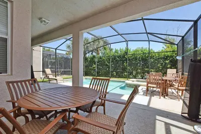 a patio with a table and chairs and a pool at Sunny Escape, Pool, Spa, Resort-3509Pp in Kissimmee