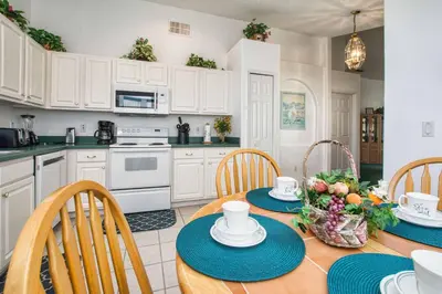 a kitchen with a table and chairs and a kitchen with white cabinets at Indian Ridge - 4 Bedroom Pool Home- 2408Ir in Orlando