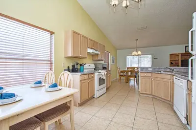 a large kitchen with wooden cabinets and a table and chairs at Indian Ridge- 4 Bedroom Pool Home- 2405Ir in Orlando