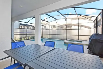 a patio with a table and chairs and a swimming pool at Comfortable Spacious-6 Bed Pool Home - 1675Str in Kissimmee