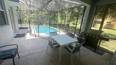 a patio with a table and chairs and a swimming pool at Pool Home With Privacy, Bbq, Mickey Room - 3500Pp in Kissimmee