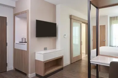 a bedroom with a tv and a bed and a mirror at SpringHill Suites by Marriott Orlando Lake Nona in Orlando