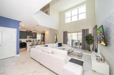 a living room with a white couch and a kitchen at 2769RP VILLA 5 BED/5 BA (SANITIZED) in Kissimmee
