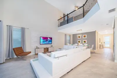 a living room with a white couch and a tv at 4352JP VILLA 5 BED/5 BA in Kissimmee